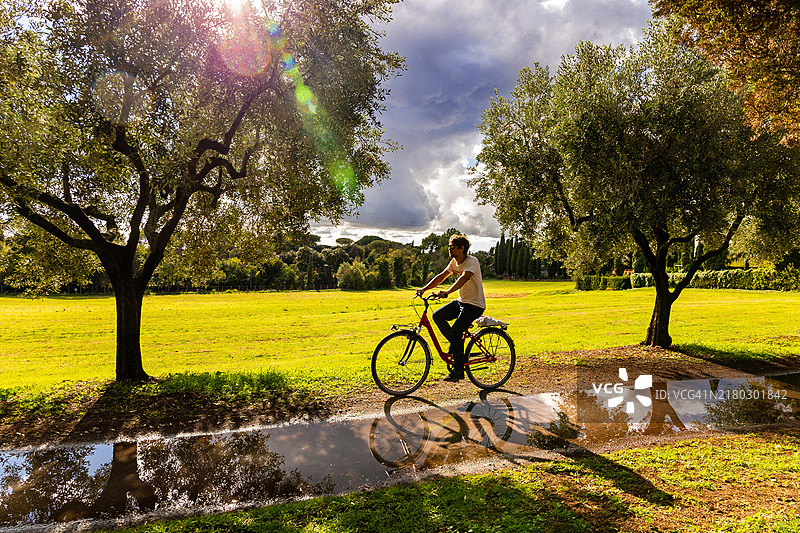骑自行车穿过风景如画的乡村公路的年轻人图片素材