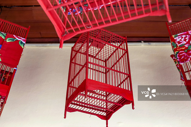 覆盖着孔雀花纹布的红色空鸟笼图片素材