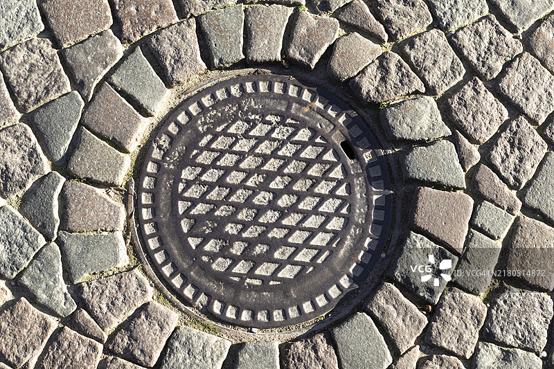 鹅卵石街道上的圆形铁盖图片素材