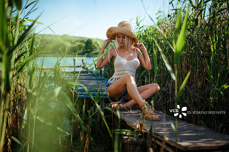 美丽的模特女孩在田野上摆姿势，享受户外自然，戴着草帽的年轻金发美女，长直金发。图片素材