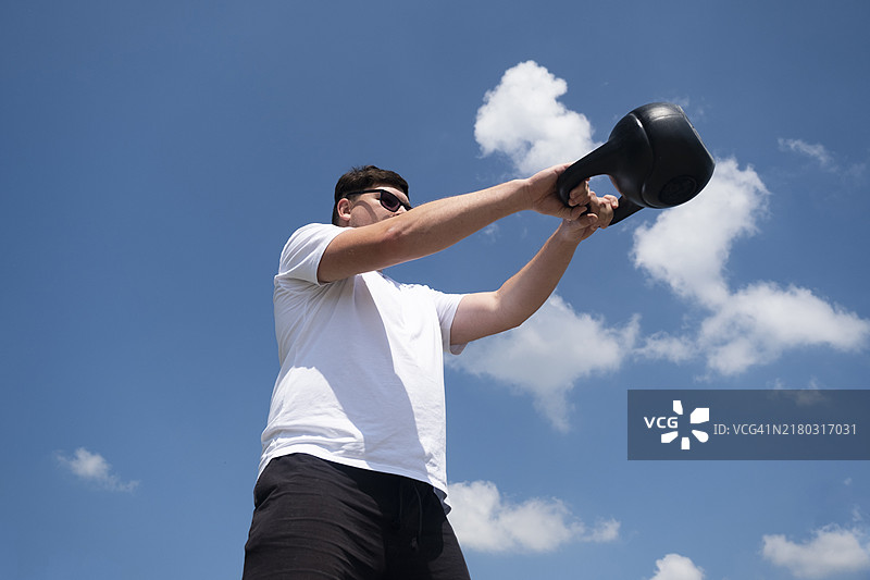 春季或夏季，运动男士在户外使用壶铃锻炼图片素材