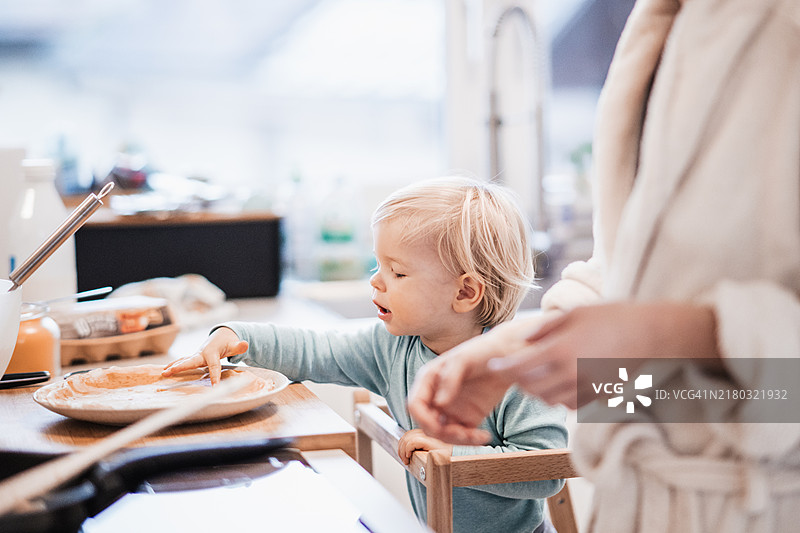 母亲和小男孩在家里的厨房一起做煎饼作为早餐图片素材