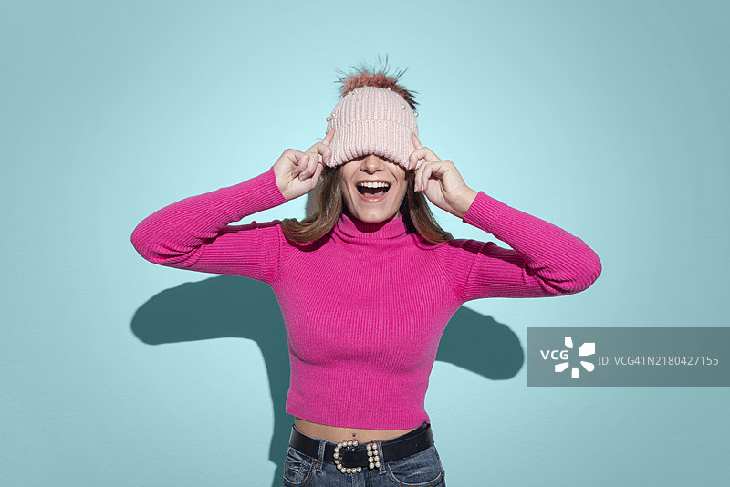 用粉色绒线帽遮住眼睛的女人图片素材