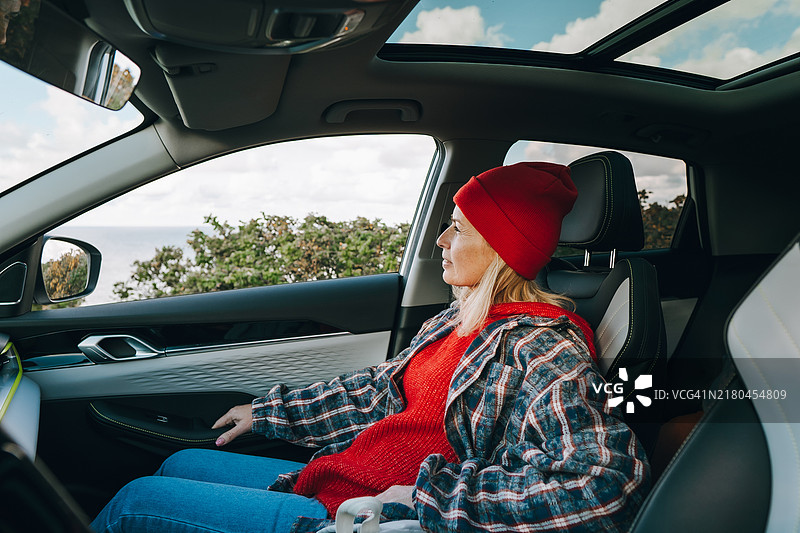 沉思的女性乘客在公路旅行中等待海边度假图片素材