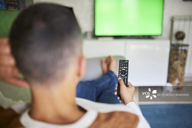 男子使用遥控器操作绿屏电视图片素材