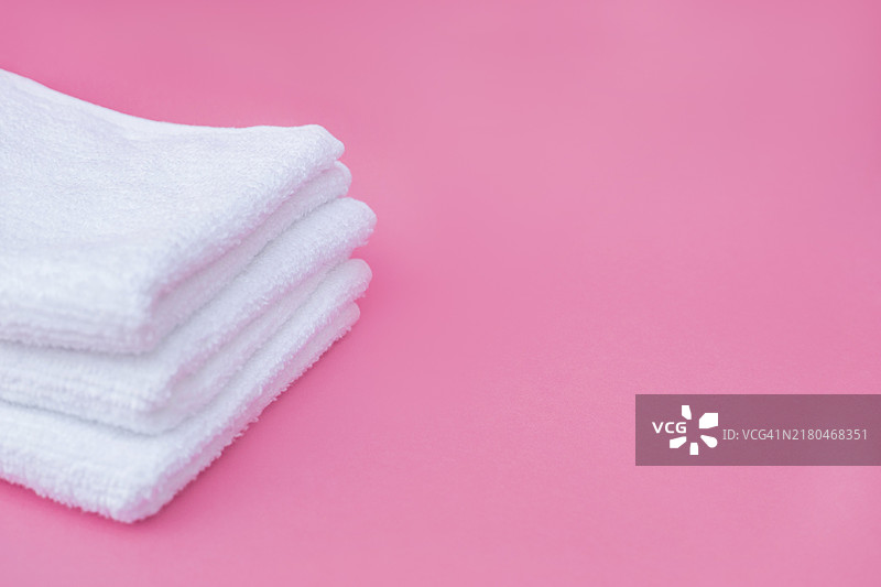 粉色背景上的白色毛巾堆图片素材