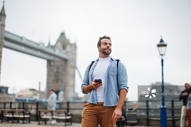 男子在伦敦塔桥探索，手持手机图片素材