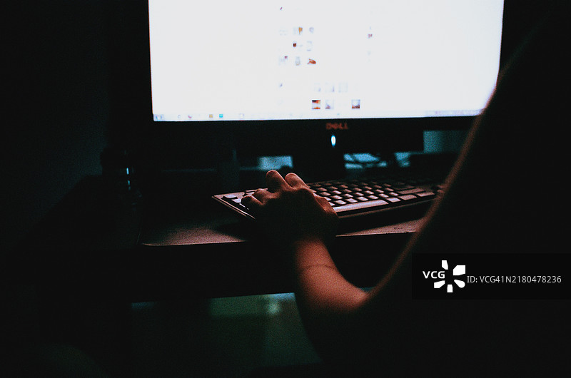 女人在黑暗中用电脑键盘打字图片素材