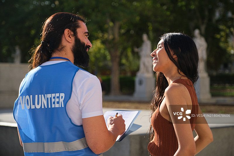 男志愿者在公园户外采访年轻女子图片素材