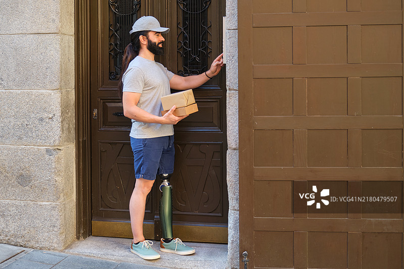 戴着假肢腿按门铃的送货员图片素材