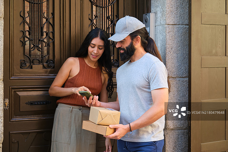 女人使用智能手机通过非接触式NFC技术支付送货费图片素材
