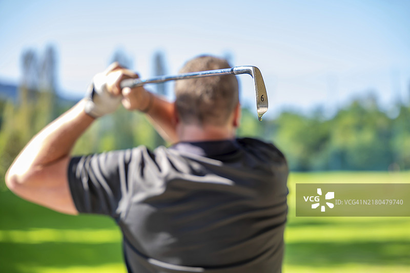 瑞士阳光明媚的一天，男人用6号铁杆挥杆图片素材