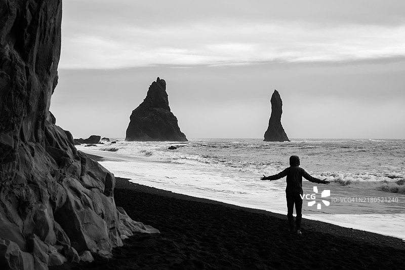 站在黑色沙滩上的男人图片素材
