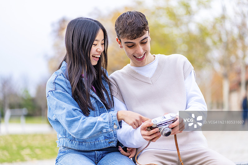 年轻人正在数码相机的屏幕上看照片图片素材