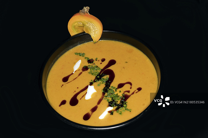 黑色背景下的南瓜奶油浓汤美食摄影图片素材