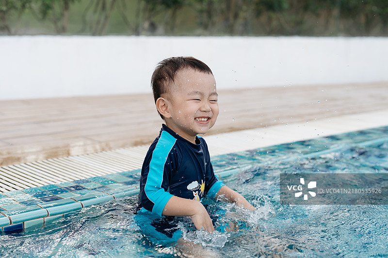 快乐的亚洲男孩在游泳池玩耍图片素材