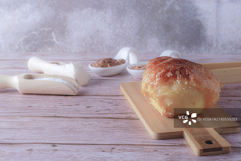 酥皮号角，内馅为糕点奶油，旁边有一些装有可可、巧克力、面粉和糖的勺子，以及一些木制夹子图片素材