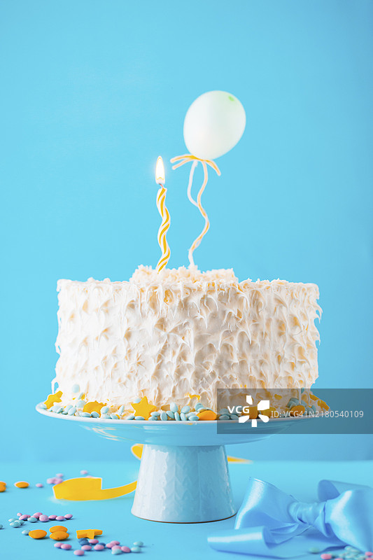 蓝色背景上的装饰蛋糕和点亮的蜡烛图片素材