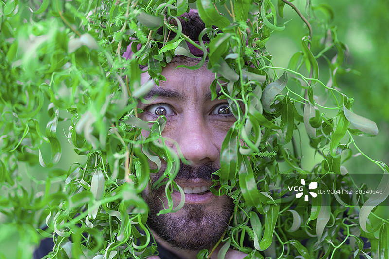 树叶中表情有趣的拉丁男人特写肖像图片素材