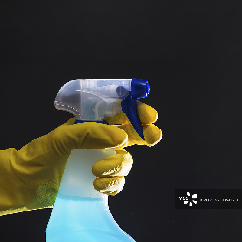 穿着黄色手套的清洁工手握喷雾瓶图片素材