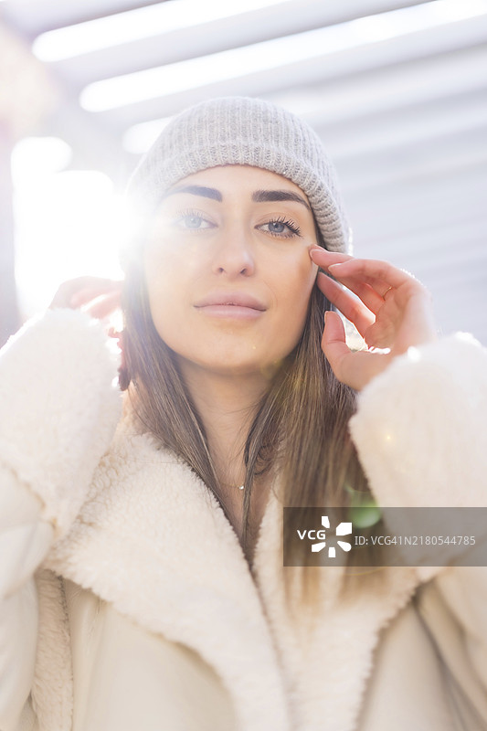 日落时分，戴着羊毛帽的白人女性在城市公园里的肖像，冬天图片素材