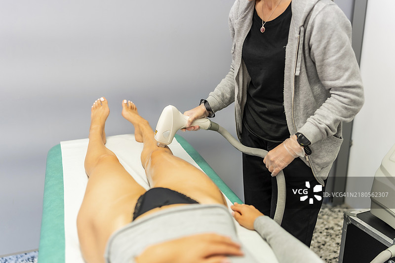 美容师用脱毛机为女性脱毛图片素材