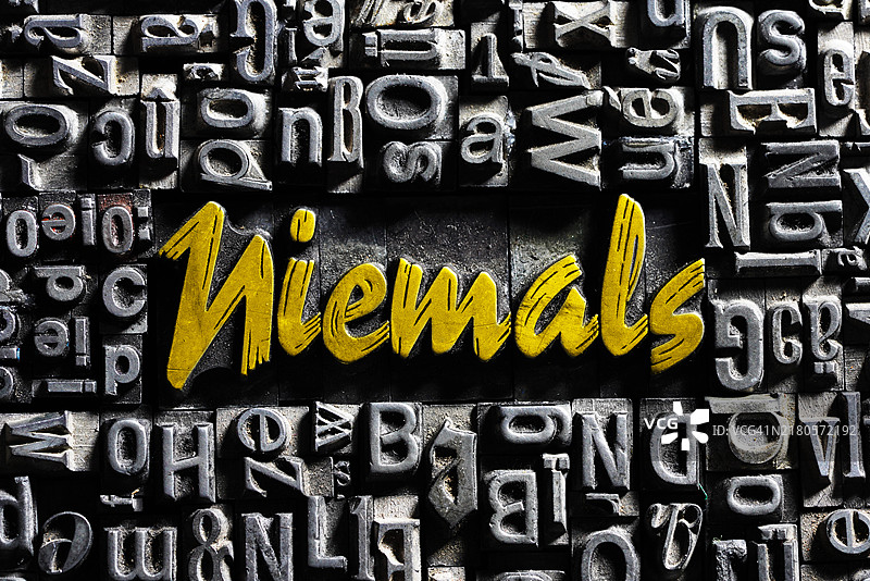 带有金色文字的旧铅字，文字为“Never”图片素材