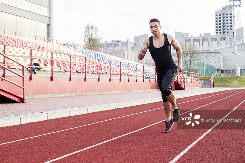 年轻男运动员在体育场跑道上跑步肖像图片素材