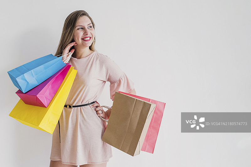 快乐的女人拿着明亮的购物袋站立图片素材