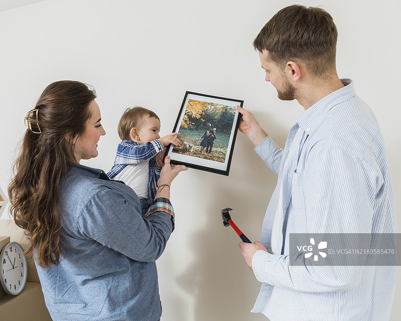 幸福夫妇和幼儿宝宝安装相框墙特写图片素材
