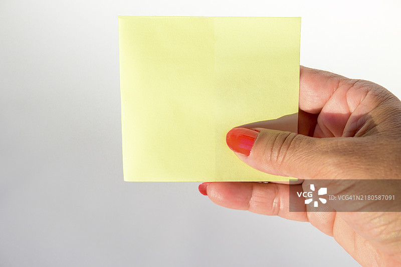 女人涂着指甲油的手拿着纯白色背景上的空白信纸图片素材