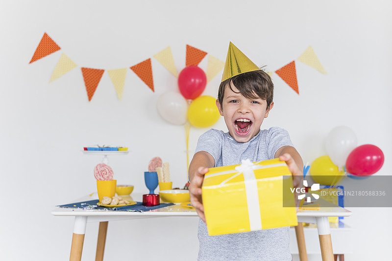 快乐男孩拿着系着白色丝带的黄色礼品盒图片素材