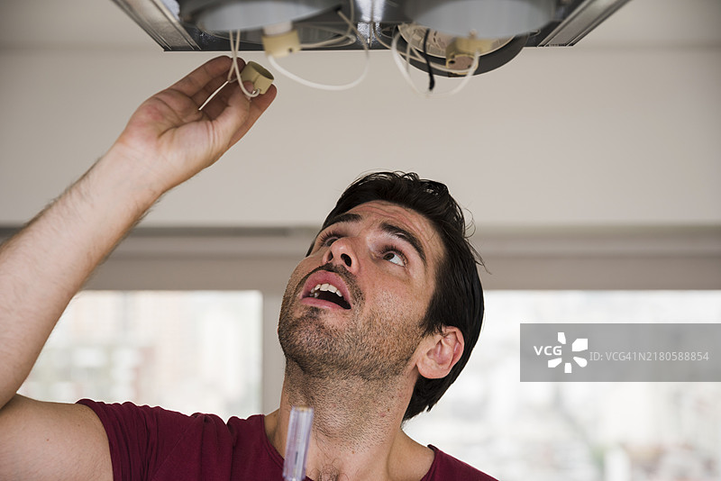 男电工安装吸顶灯支架特写图片素材