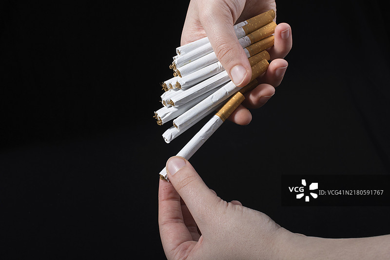 在黑色背景上手里拿着一包香烟图片素材