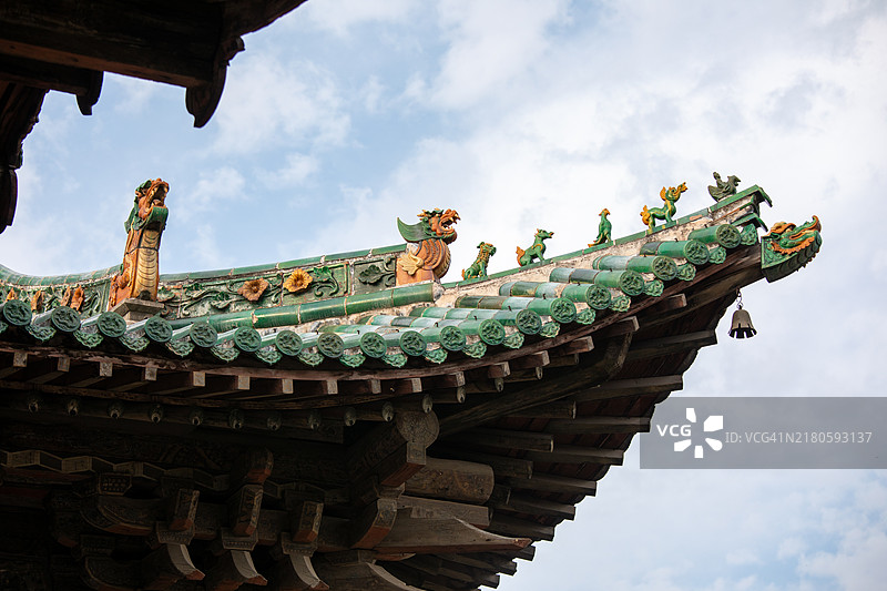 古老的飞檐结构，配有琉璃屋顶兽、瓦片和木质斗拱框架。图片素材