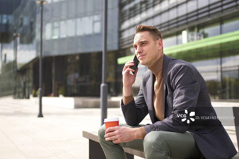 年轻商人使用手机发短信和与人交谈图片素材