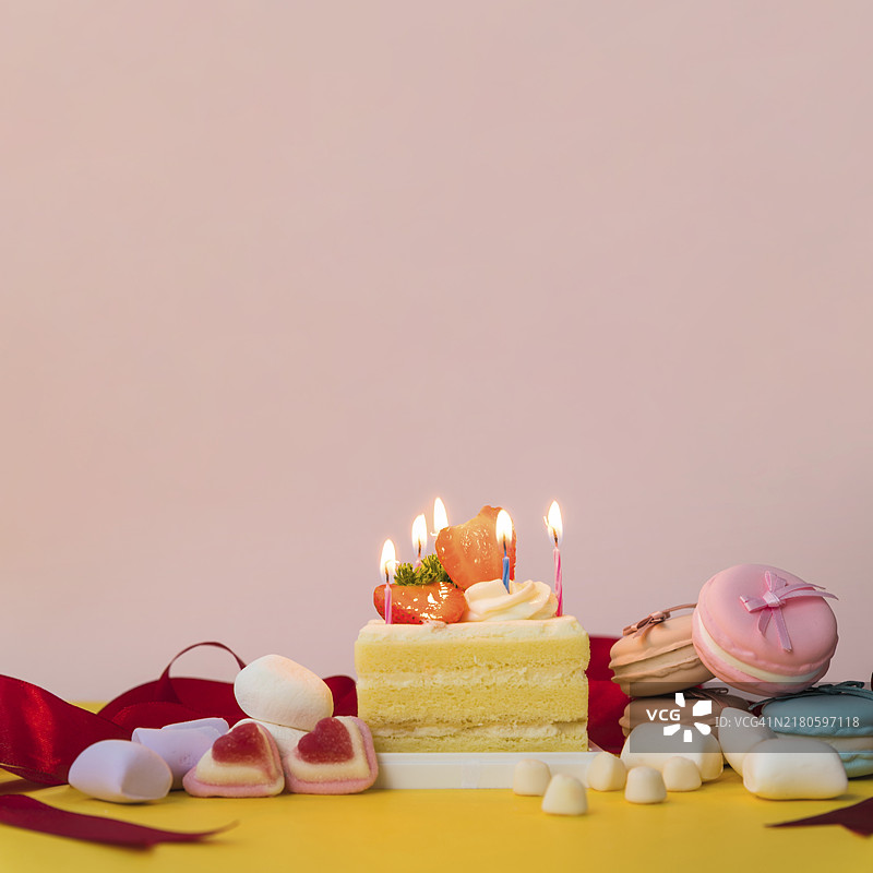 糖果棉花糖马卡龙装饰的蛋糕，黄色桌面图片素材