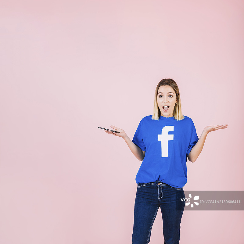 拿着智能手机，惊讶的年轻女人肖像图片素材