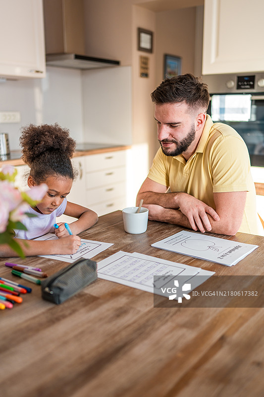 专注的混血女孩和白人父亲在家学习图片素材