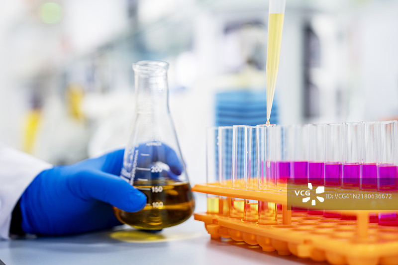 在实验室工作的亚洲科学家用移液管将化学物质滴入试管的特写图片素材
