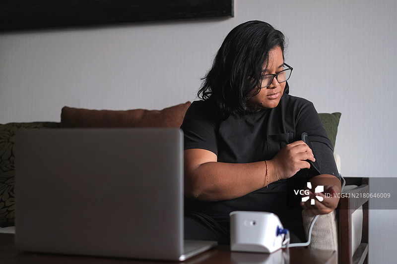 中年印度尼西亚妇女用电子仪器自我监测血压图片素材