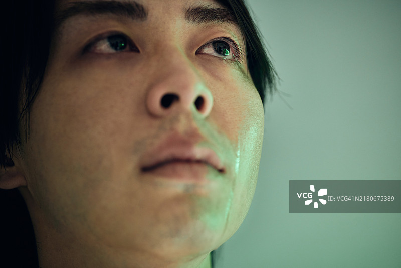 工作室里一个眼里含着泪水的年轻人的倾斜肖像图片素材