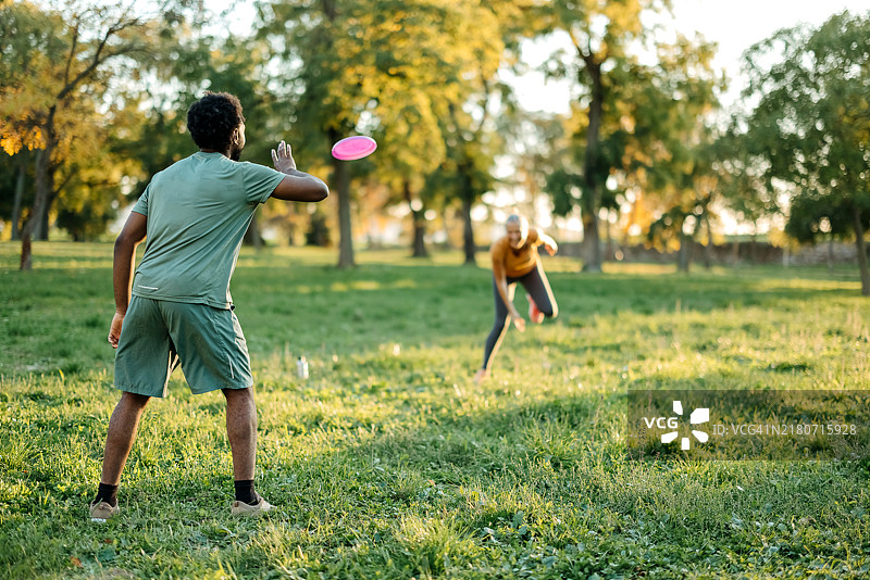 一对情侣在公园里玩飞盘图片素材