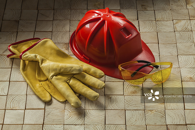建筑手套、安全护目镜和红色头盔，木质背景图片素材