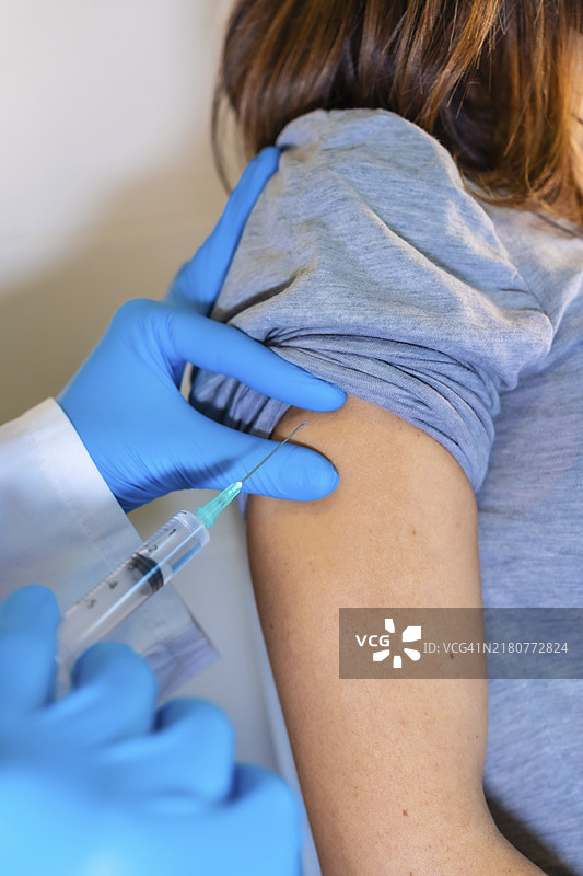 女医生为年轻孕妇接种新冠疫苗。竖版照片图片素材