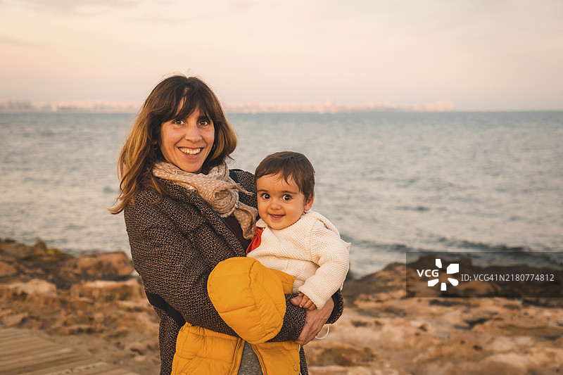 生活方式：海滩上，一位母亲在海边拥抱她的宝宝图片素材