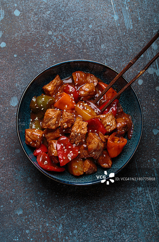 蓝色盘子里的甜酸猪肉配青椒和菠萝图片素材