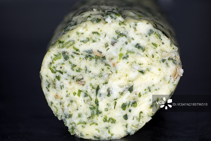 卷状自制香草黄油，黑色背景下的工作室摄影图片素材