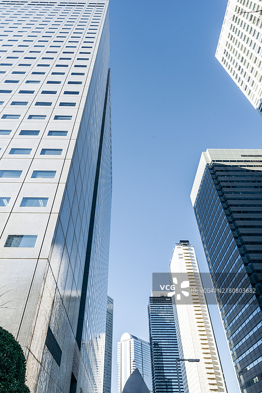 现代摩天大楼在商业区的清澈蓝天下，城市建筑视角。图片素材