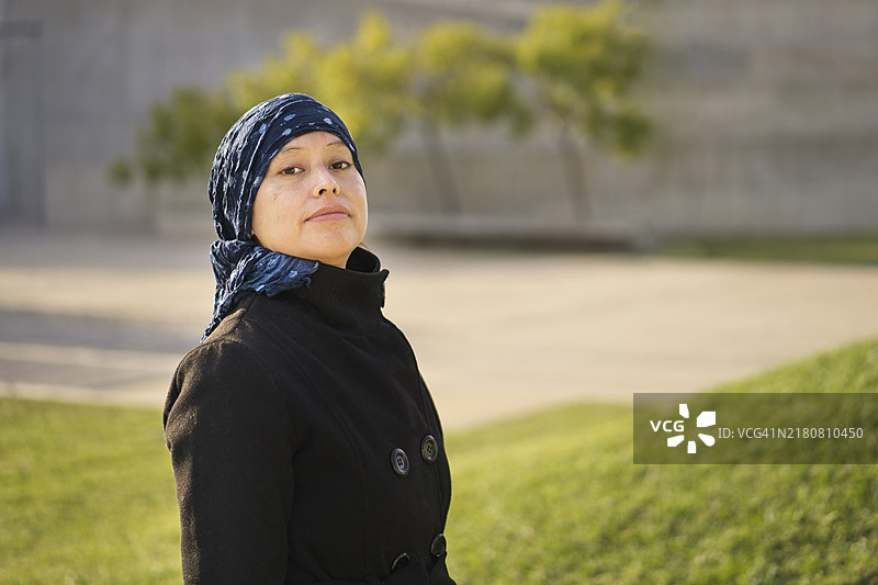 一位接受癌症治疗的拉丁裔妇女的肖像，她头上戴着一条围巾，表情坚强图片素材